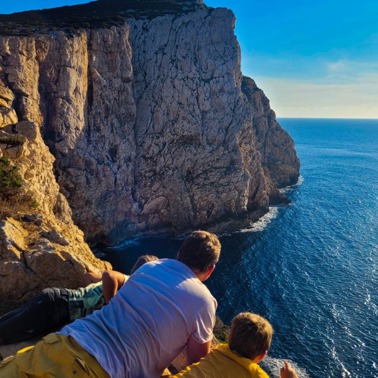 Gezin liggend op een hoge rots, rondreis Sardinië